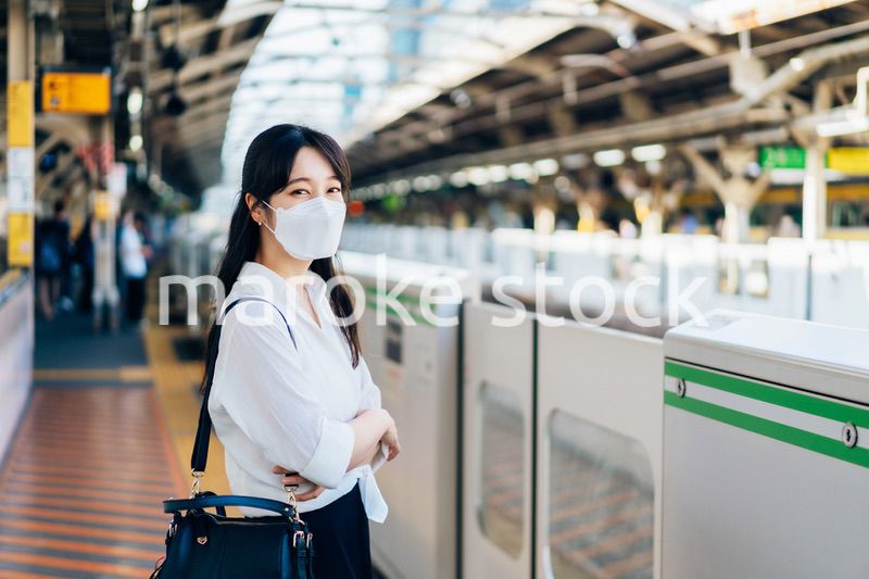 マスクをして電車を待つ若い女性
