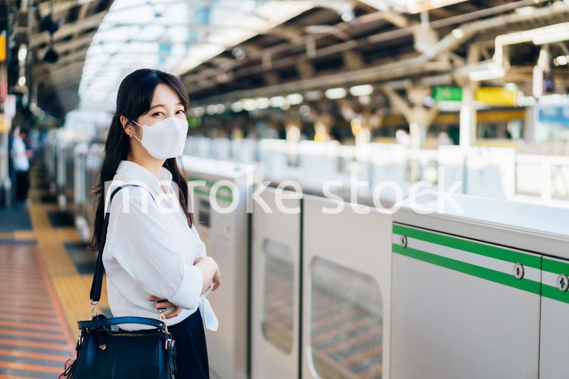 マスクをして電車を待つ若い女性