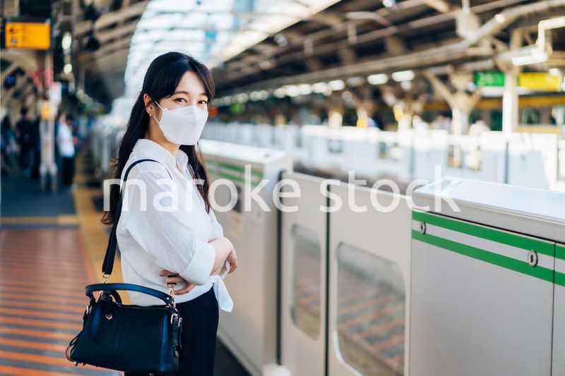 マスクをして電車を待つ若い女性