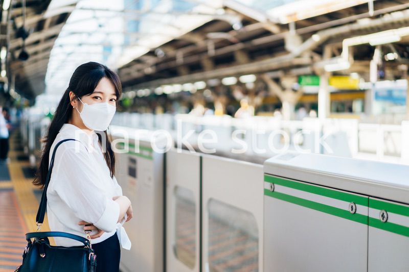 マスクをして電車を待つ若い女性