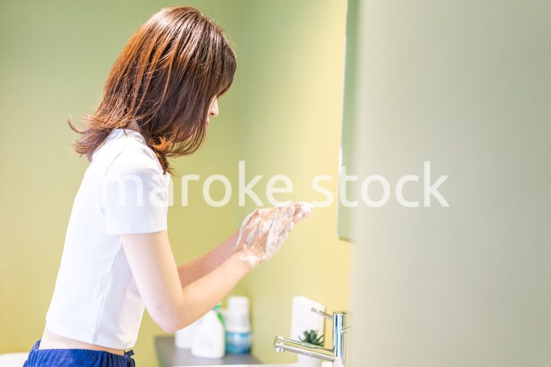 洗面台で顔を洗う若い女性