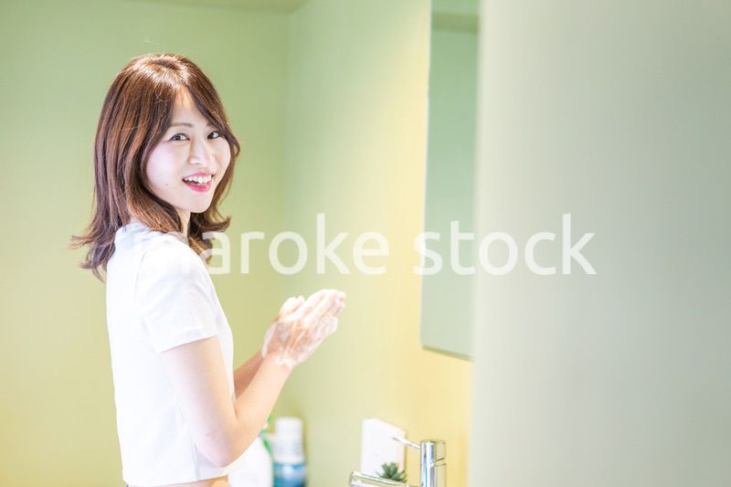 洗面台で顔を洗う若い女性