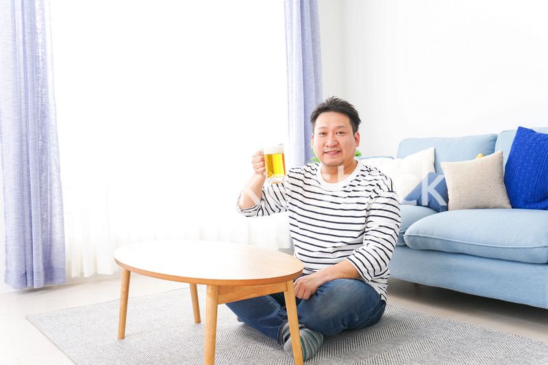 自宅でビールを飲む中年の男性