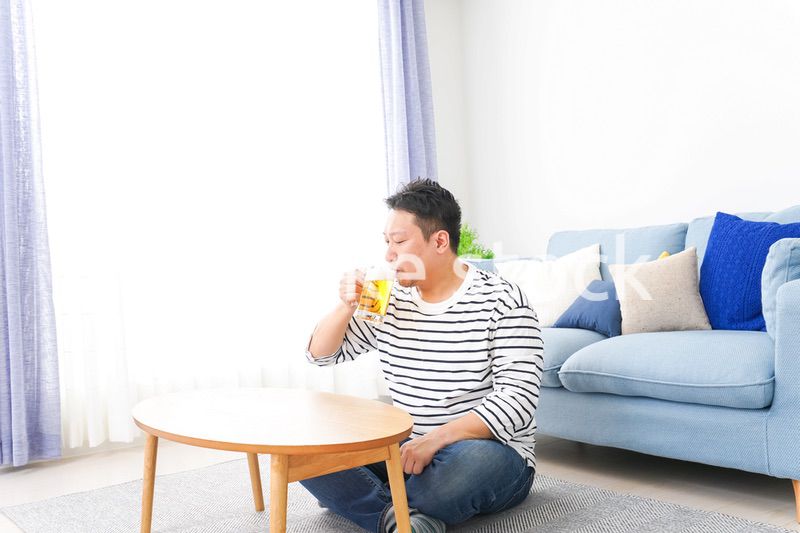 自宅でビールを飲む中年の男性