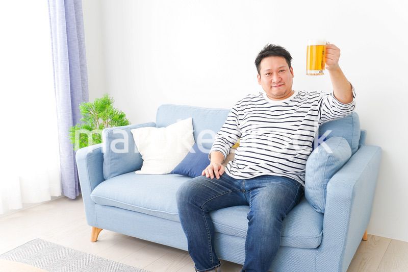 自宅でビールを飲む中年の男性