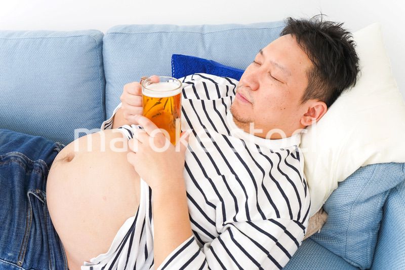 自宅でビールを飲む中年の男性