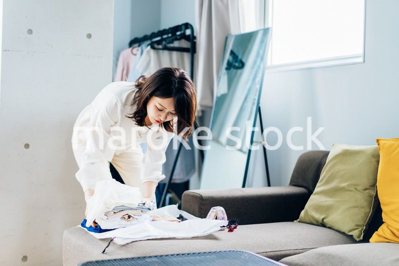 自宅で洗濯物をたたむ若い女性