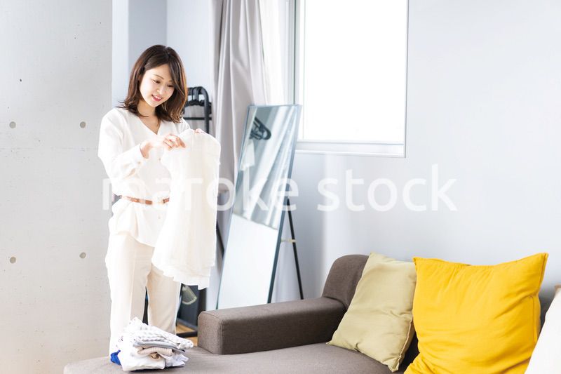 自宅で洗濯物をたたむ若い女性