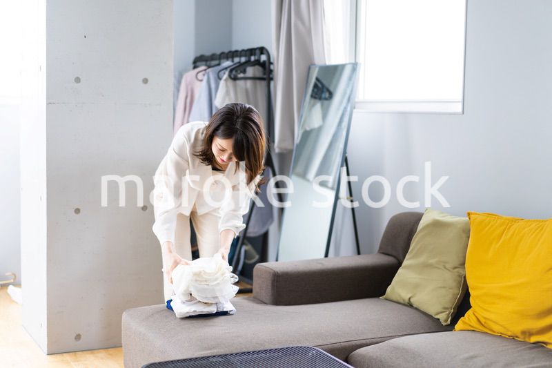 自宅で洗濯物をたたむ若い女性