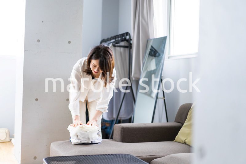 自宅で洗濯物をたたむ若い女性