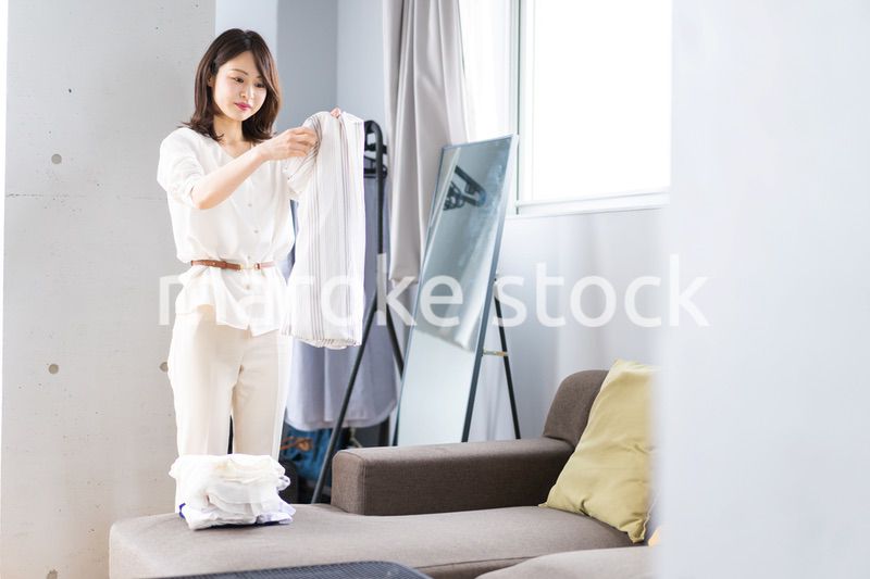 自宅で洗濯物をたたむ若い女性