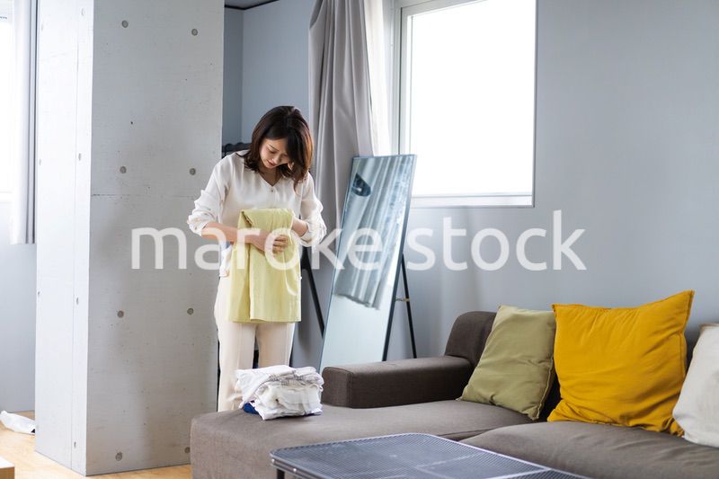 自宅で洗濯物をたたむ若い女性