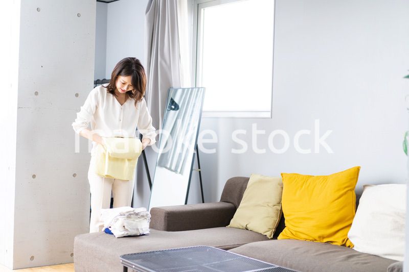 自宅で洗濯物をたたむ若い女性