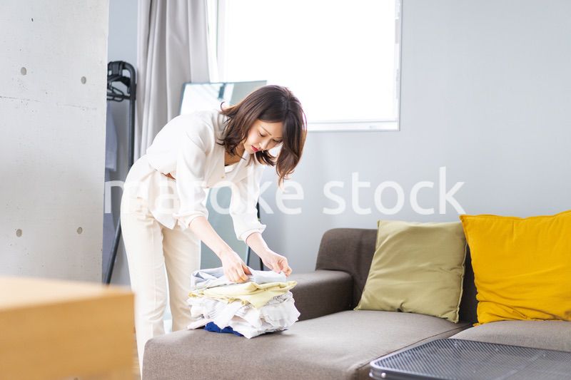 自宅で洗濯物をたたむ若い女性