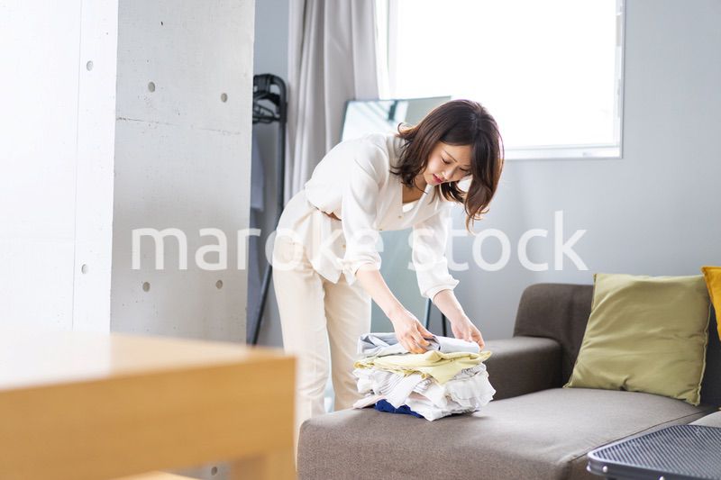 自宅で洗濯物をたたむ若い女性