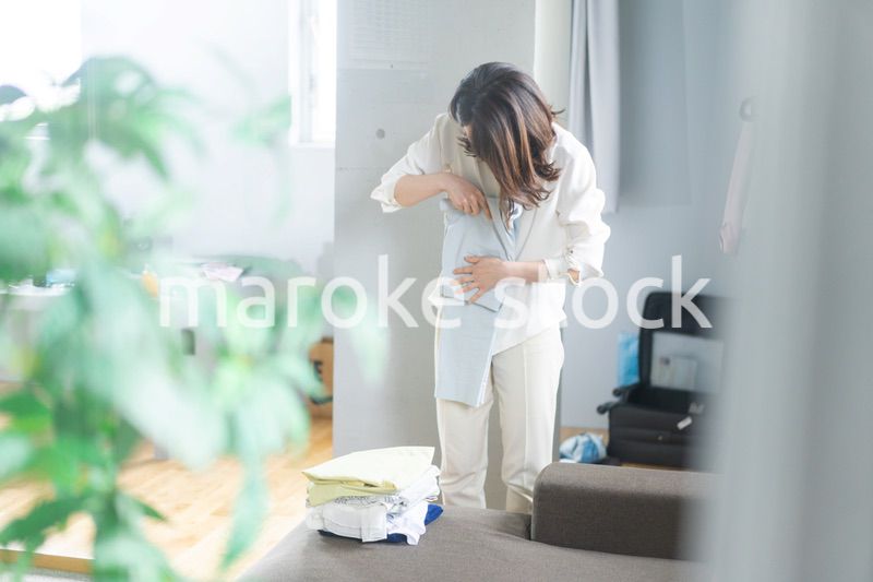 自宅で洗濯物をたたむ若い女性