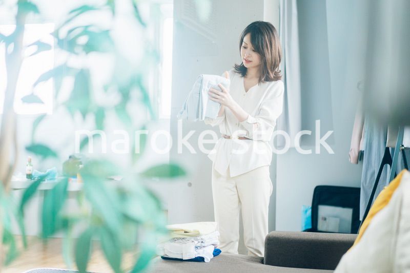 自宅で洗濯物をたたむ若い女性