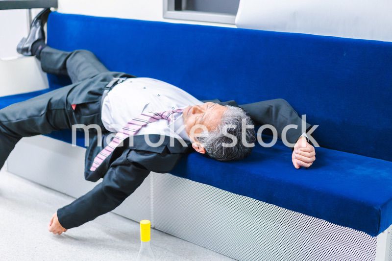 電車内で寝転ぶ中年男性