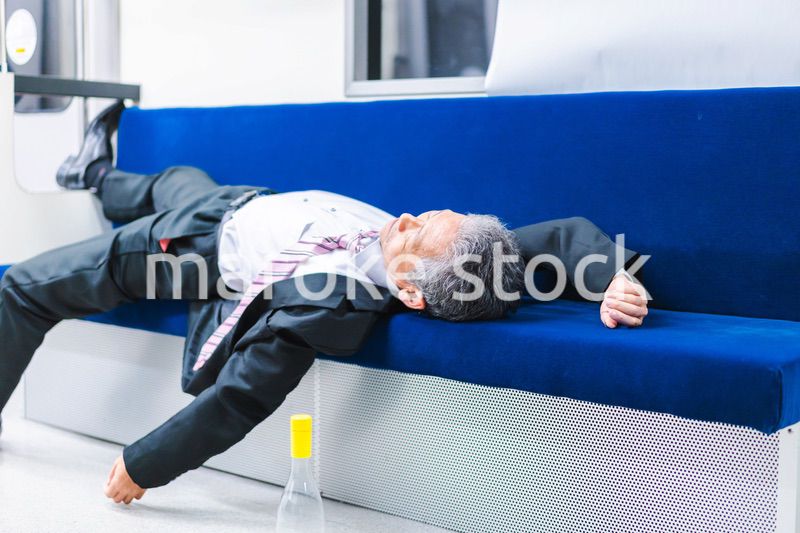 電車内で寝転ぶ中年男性