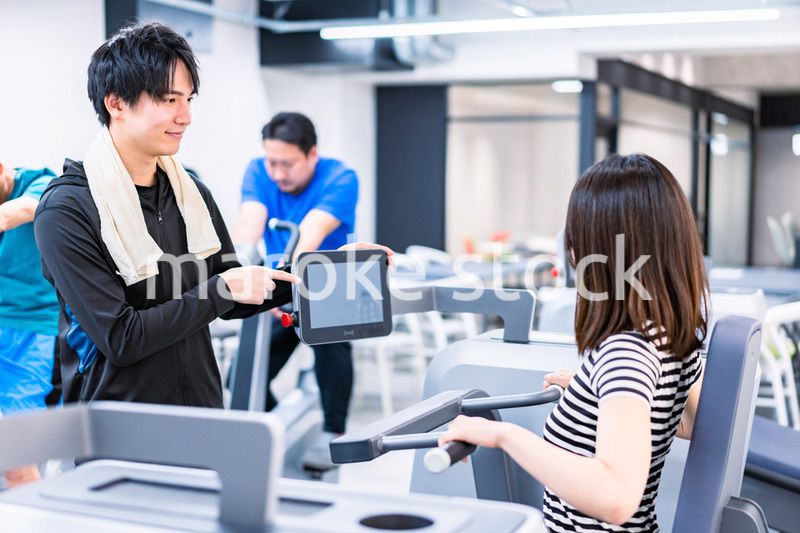 ジムでトレーナーの指導を受ける若い女性