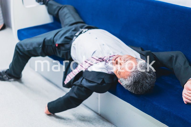 電車内で寝転ぶ中年男性