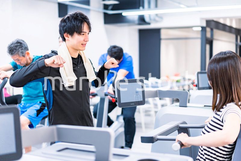 ジムでトレーナーの指導を受ける若い女性