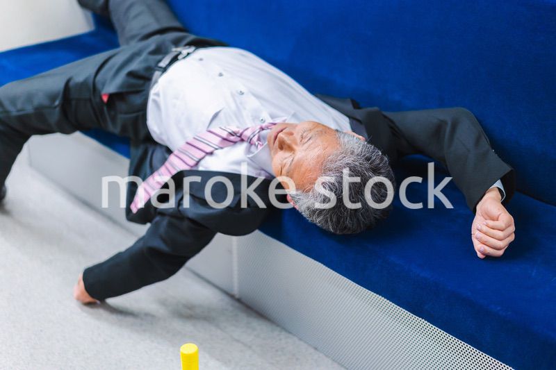 電車内で寝転ぶ中年男性