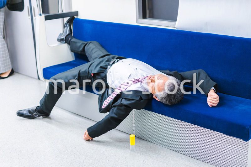 電車内で寝転ぶ中年男性