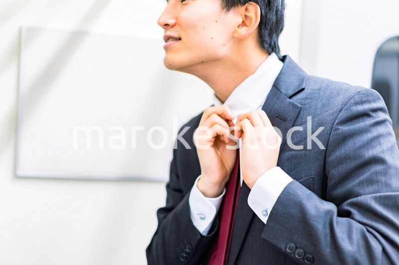 電車内でネクタイを締める男性