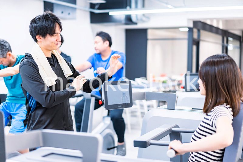 ジムでトレーナーの指導を受ける若い女性