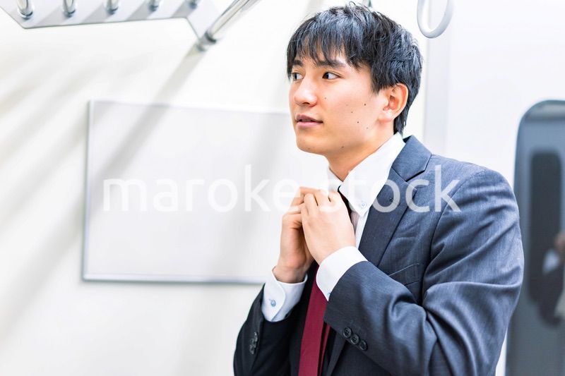 電車内でネクタイを締める男性