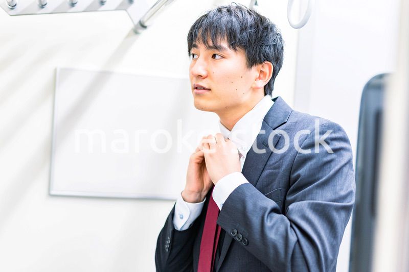 電車内でネクタイを締める男性