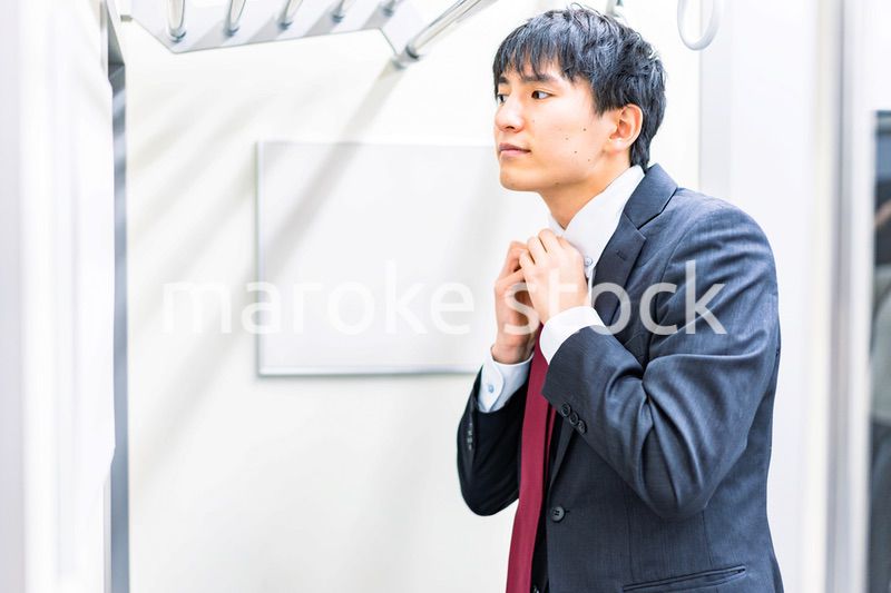 電車内でネクタイを締める男性