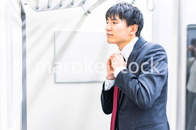 電車内でネクタイを締める男性