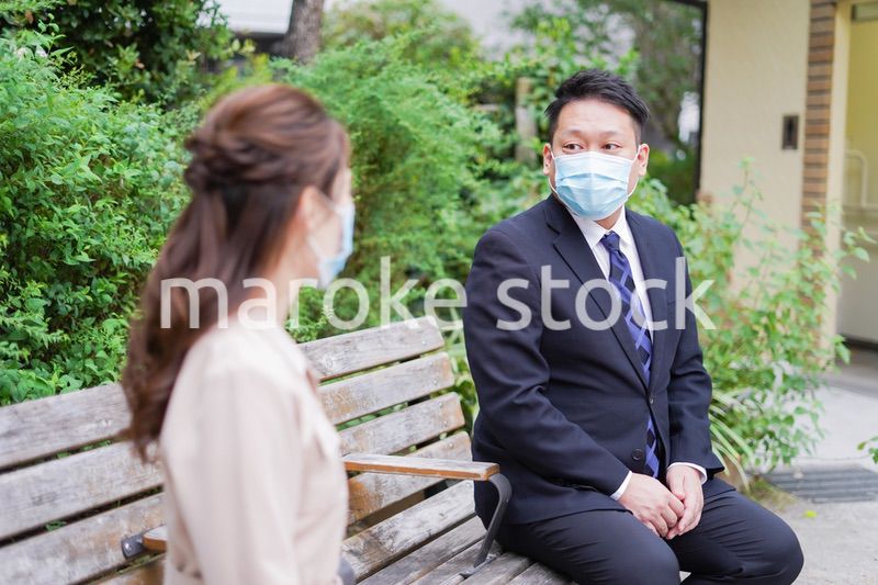 ソーシャルディスタンスを確保して会話をするビジネスパーソン