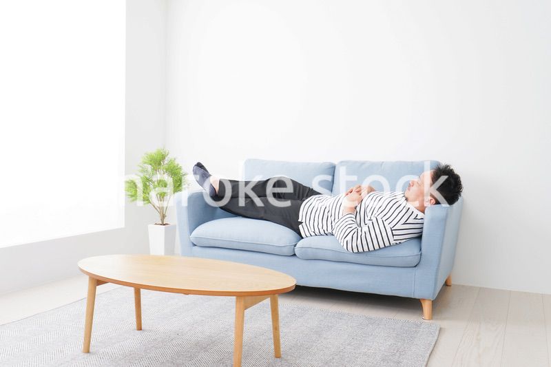 自宅で昼寝をする中年の男性