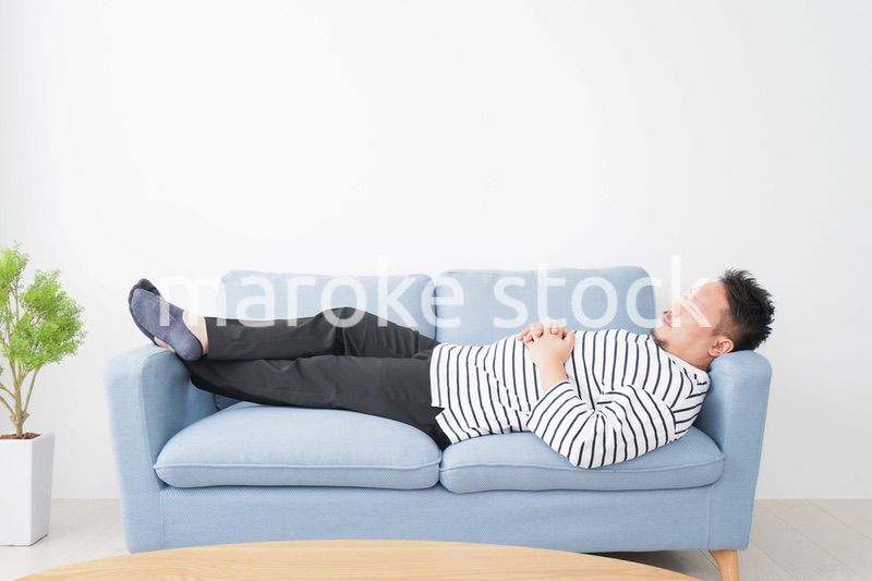 自宅で昼寝をする中年の男性