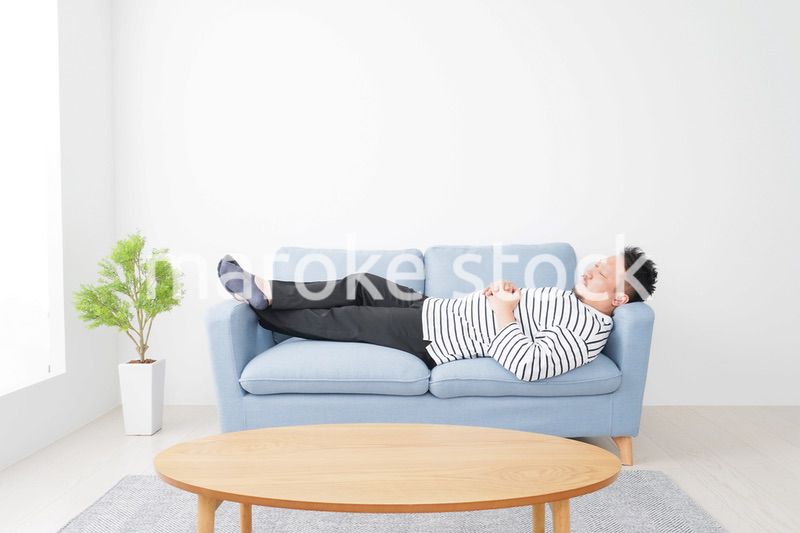 自宅で昼寝をする中年の男性