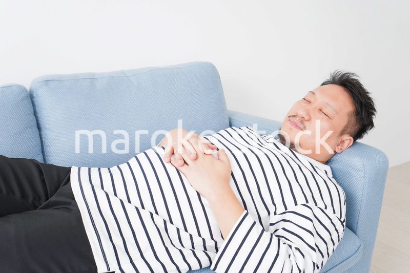 自宅で昼寝をする中年の男性