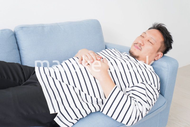 自宅で昼寝をする中年の男性