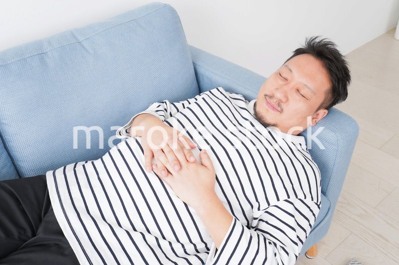 自宅で昼寝をする中年の男性