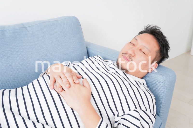 自宅で昼寝をする中年の男性