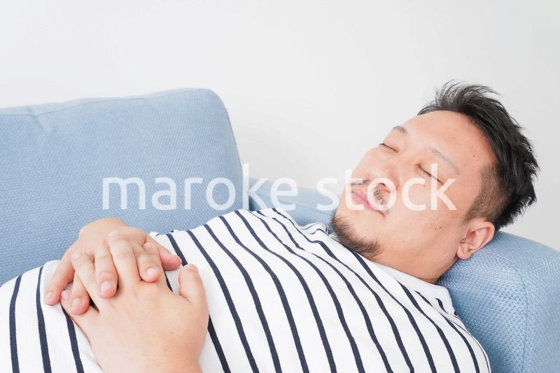 自宅で昼寝をする中年の男性