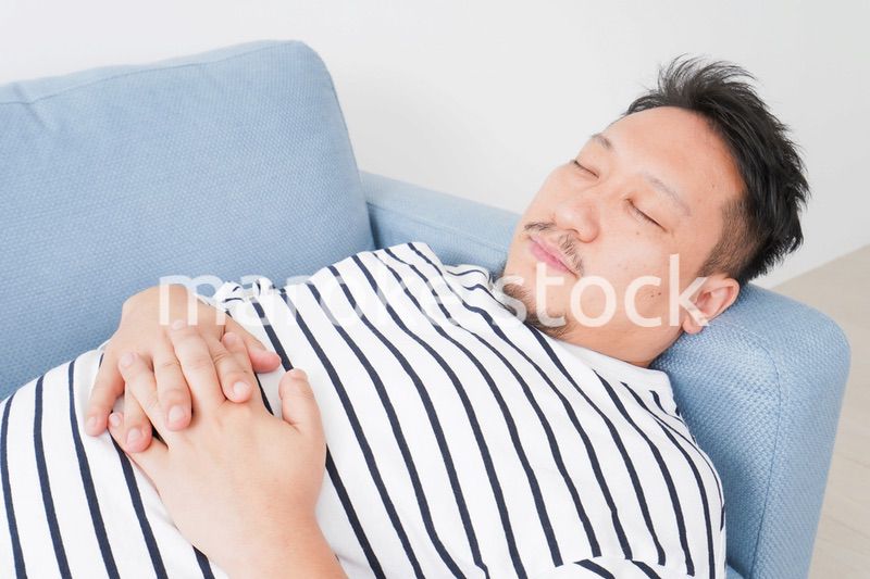 自宅で昼寝をする中年の男性