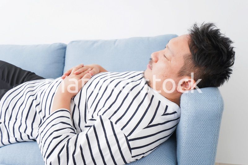自宅で昼寝をする中年の男性