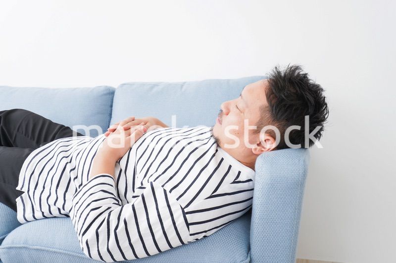 自宅で昼寝をする中年の男性