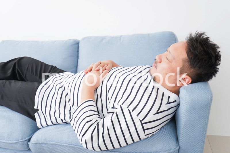 自宅で昼寝をする中年の男性