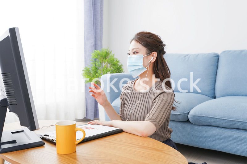 マスクをしてオンライン会議に参加する若いビジネスウーマン