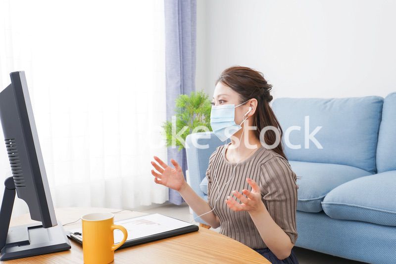 マスクをしてオンライン会議に参加する若いビジネスウーマン