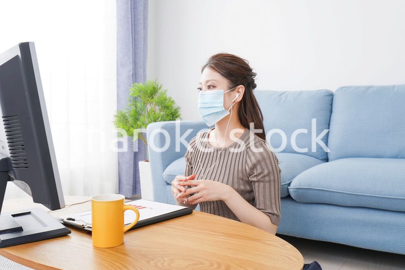マスクをしてオンライン会議に参加する若いビジネスウーマン